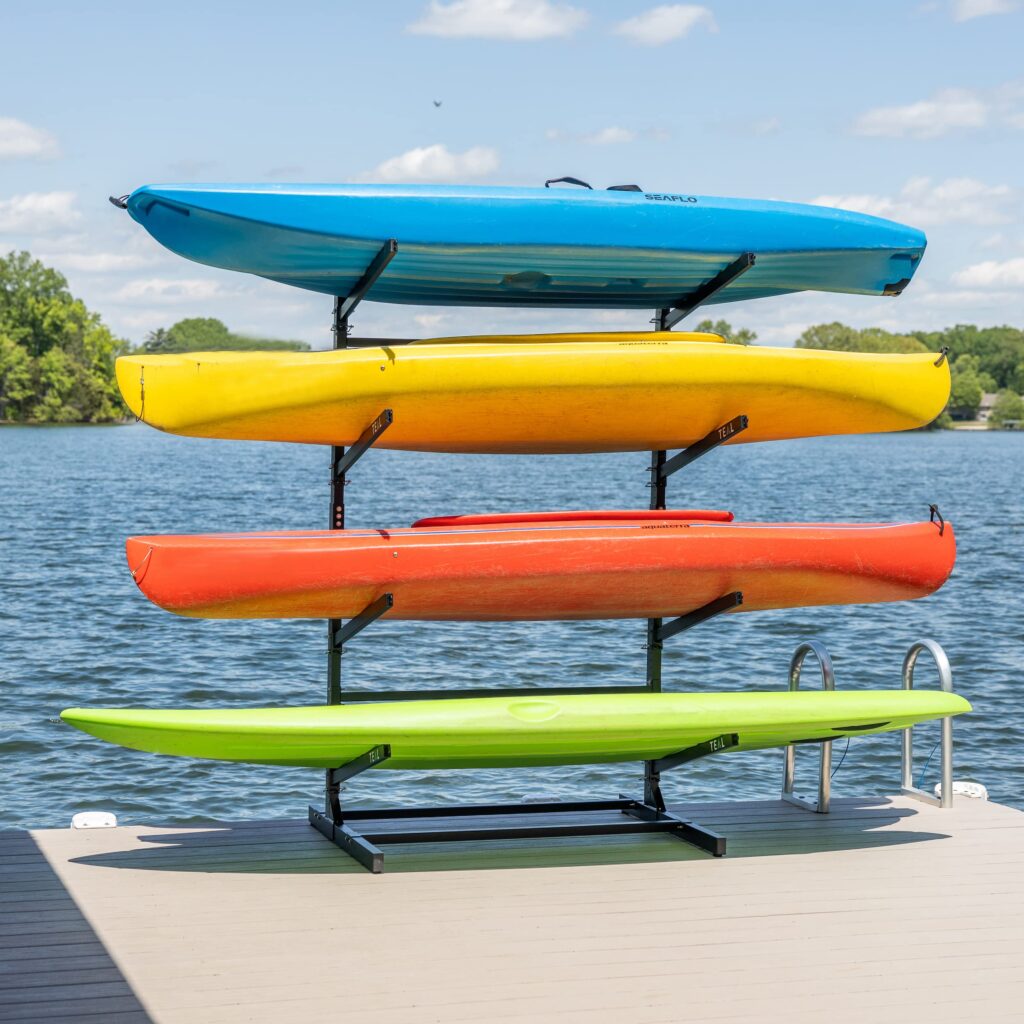 A four position freestanding kayak rack with three kayaks and a stand up paddleboard on it.