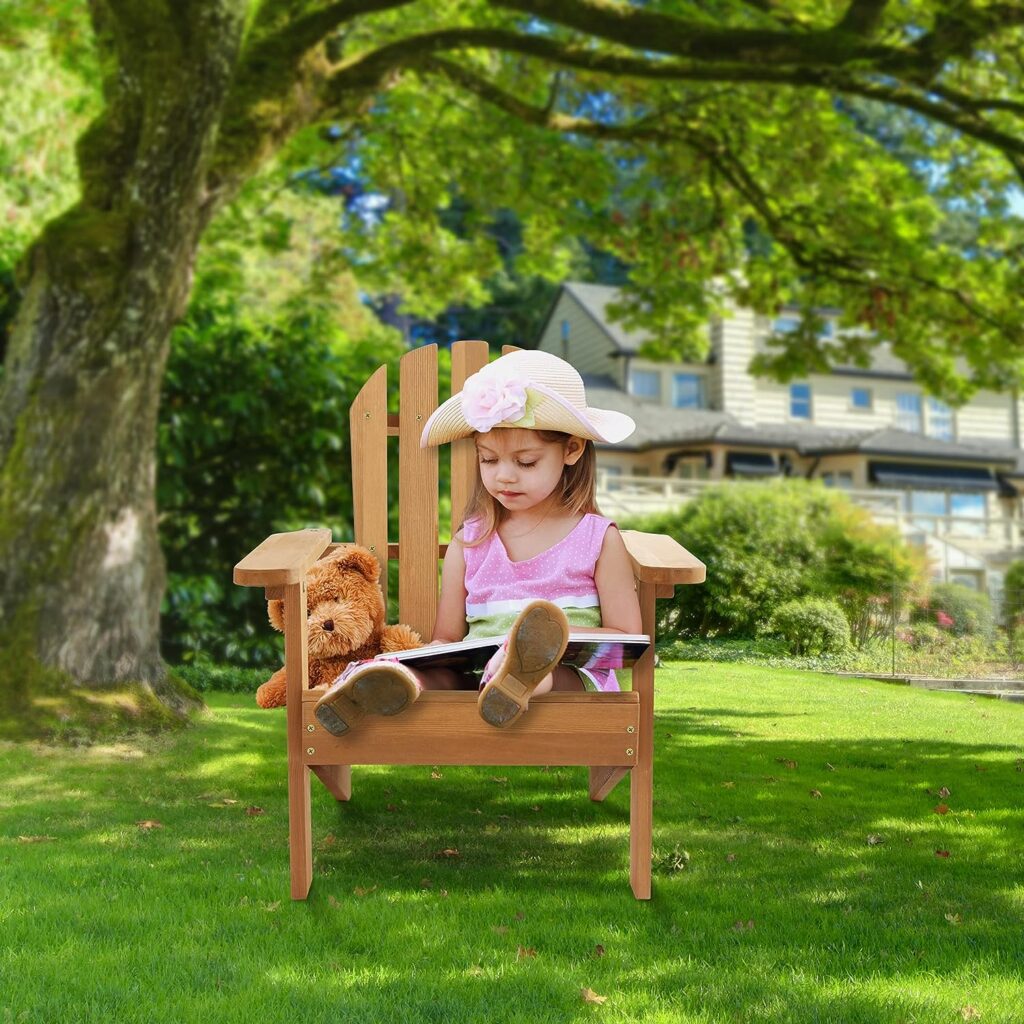Young child sitting in a child size Adirondack chair with a teddy bear.