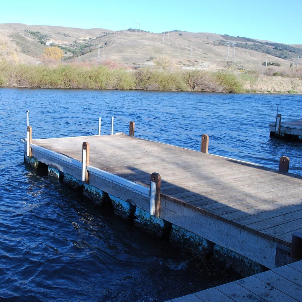 Wooden boat dock with white dock bumpers on it.