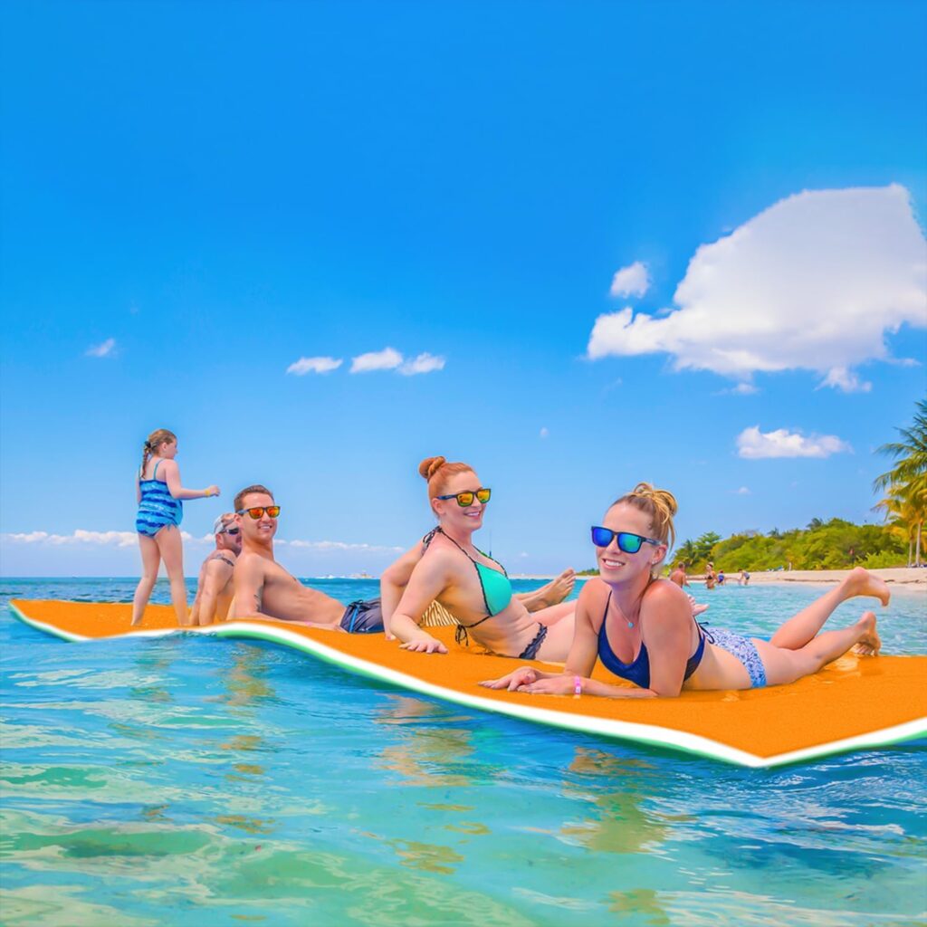 men, women, and children in swimsuits on a floating mat in a lake