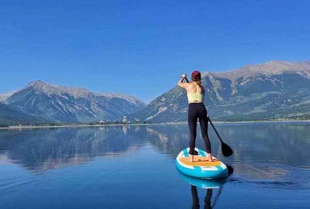 woman on an inflatable stand up paddle board floating on a mountain lake